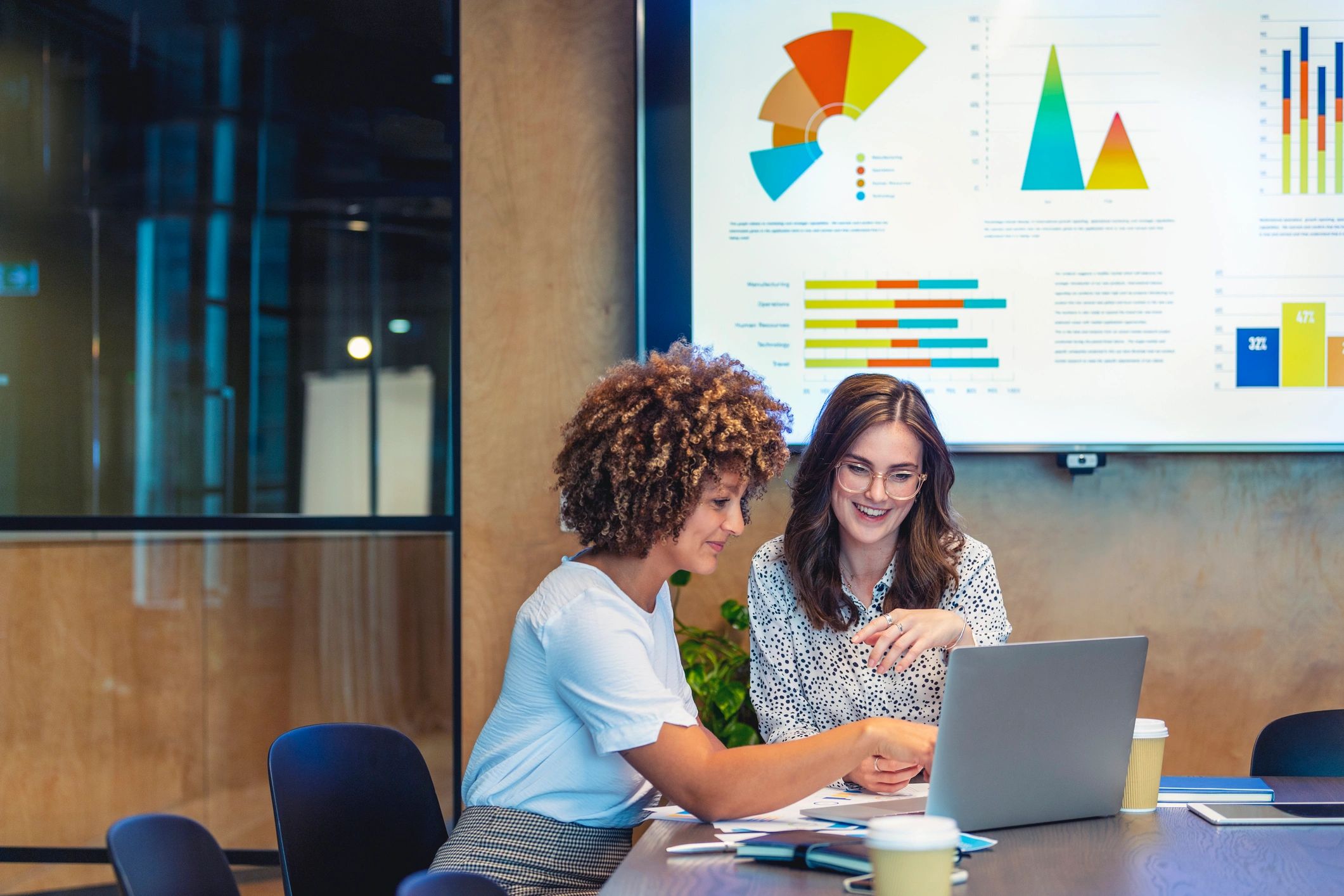 Professionals collaborating on a laptop with charts in a meeting room
